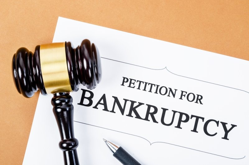 Close-up of a judge’s gavel resting on a document labeled “Petition for Bankruptcy.”