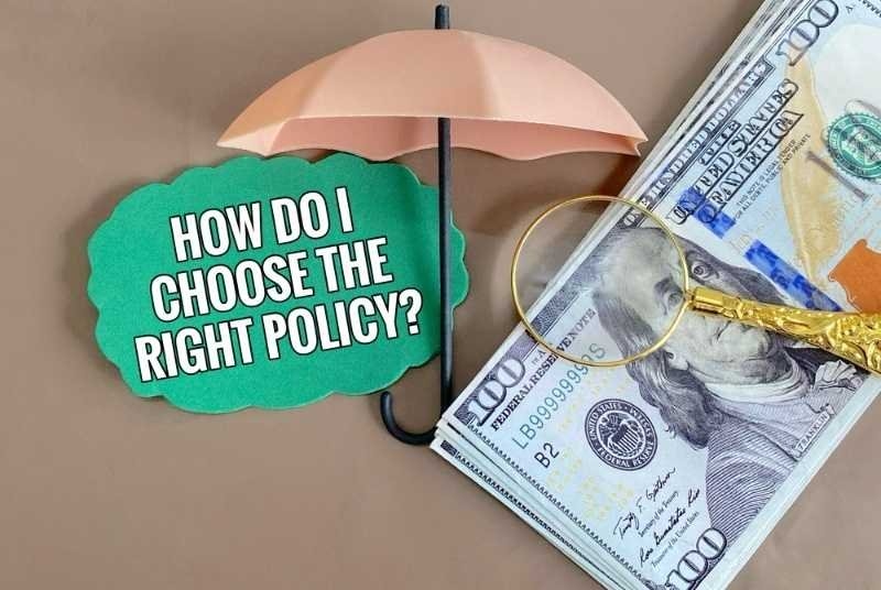 Umbrella, magnifying glass, and U.S. dollar bills surrounding a sign reading "How Do I Choose the Right Policy?"