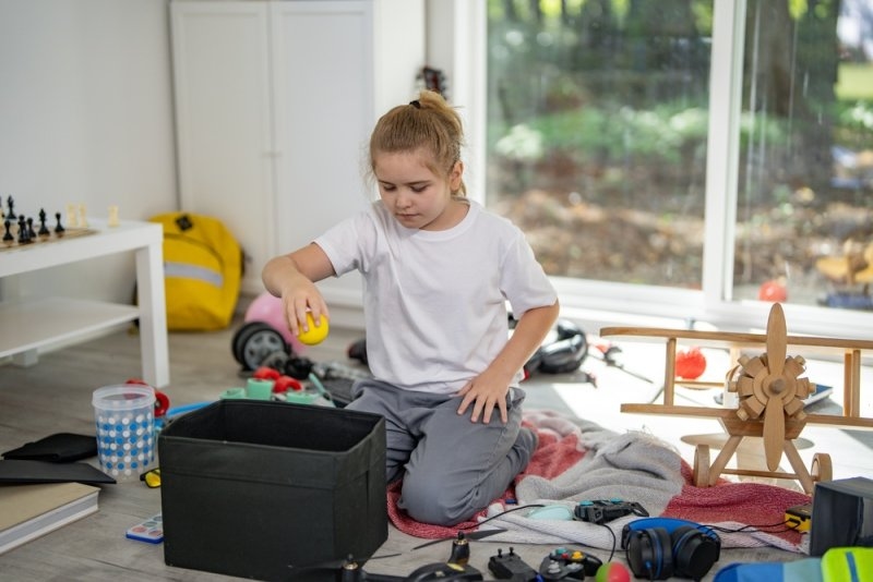 Child cleaning messy playroom at home