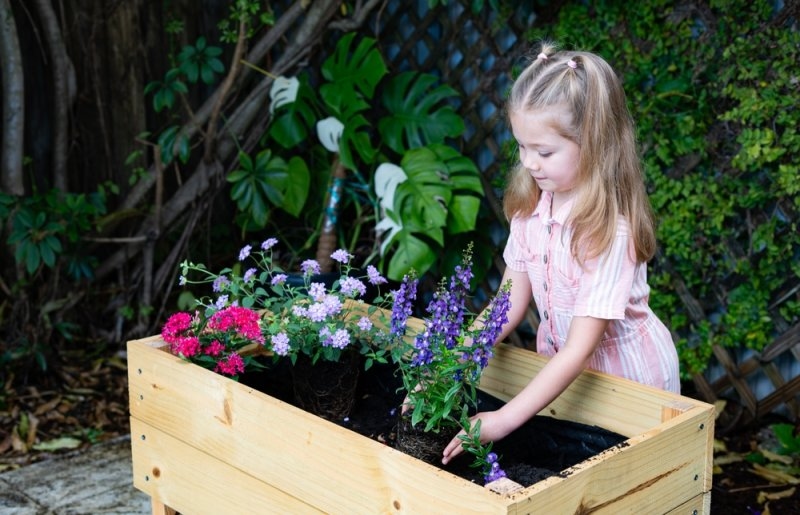 child planting flower pot in backyard