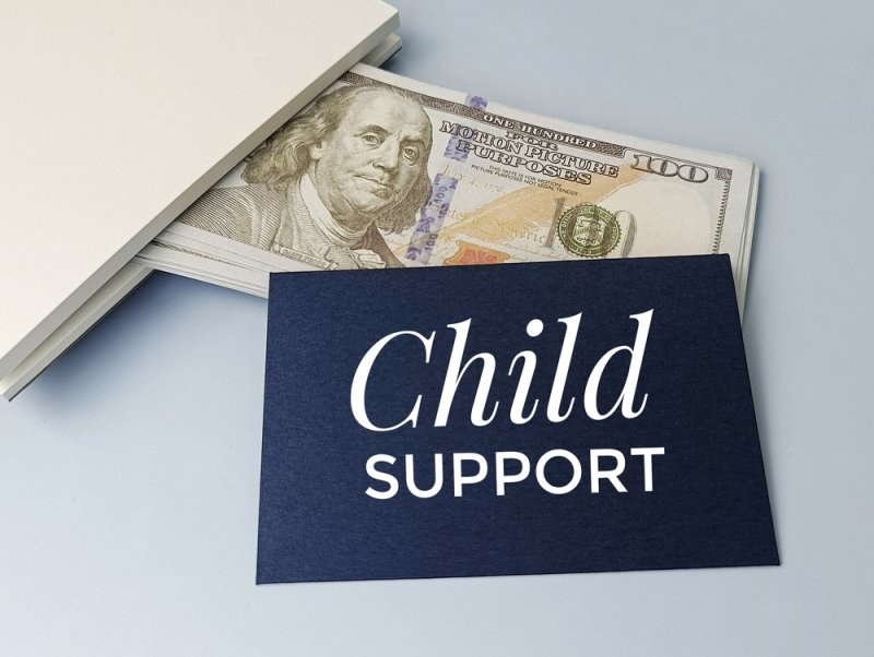 Child support concept featuring U.S. dollar bills and a card labeled “Child Support.”