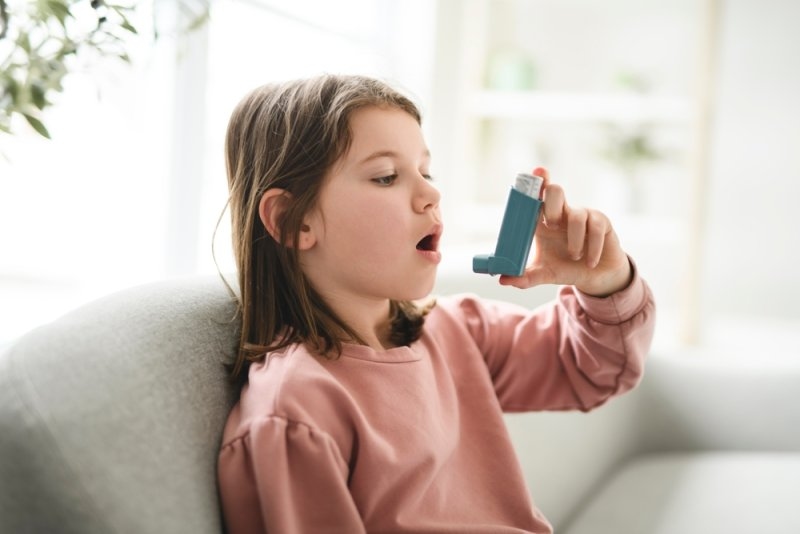 child having breathing problems and using an asthma inhaler