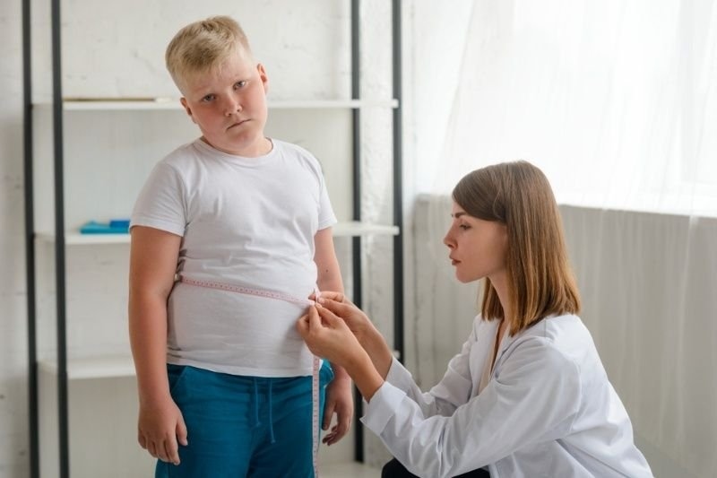 Upset boy during waistline measurement at a nutritionist's appointment. Tracking excess weight to handle child's obesity.