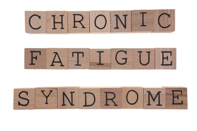 Wooden letter blocks spelling ‘Chronic Fatigue Syndrome’ on a white background.