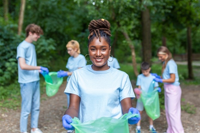 Volunteers collecting litter in a green outdoor area.