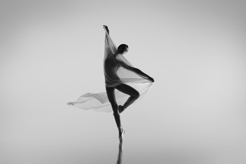 Black and white portrait of graceful ballerina dancing with fabric