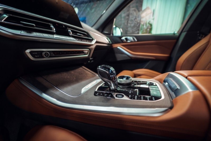 Luxury car interior featuring a premium dashboard, center console, gear selector, and brown leather seats.