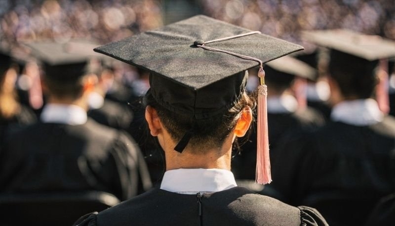 View of University Graduate Wearing Cap and Gown at Graduation Ceremony.
