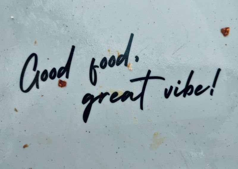 Handwritten message reading "Good food, great vibe!" on a light-colored surface.