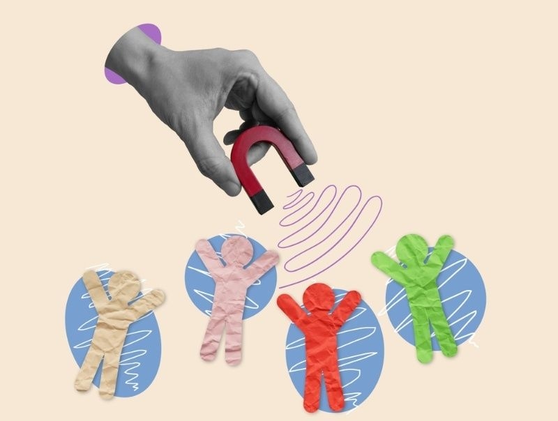 Hand holding a magnet attracting colorful human-shaped figures, representing talent attraction or influence.