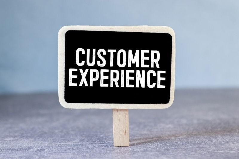 Small tabletop sign displaying the words "Customer Experience" against a blurred background.
