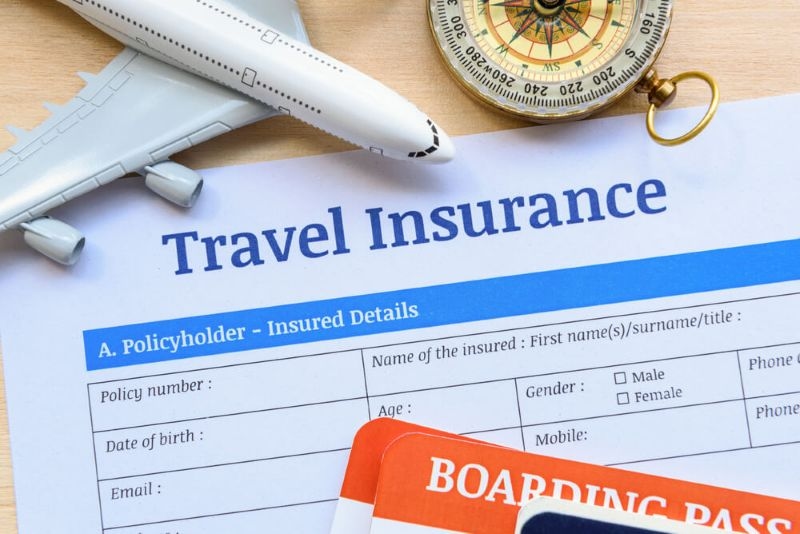 Travel insurance form put on a wooden table with mini plane toy and compass
