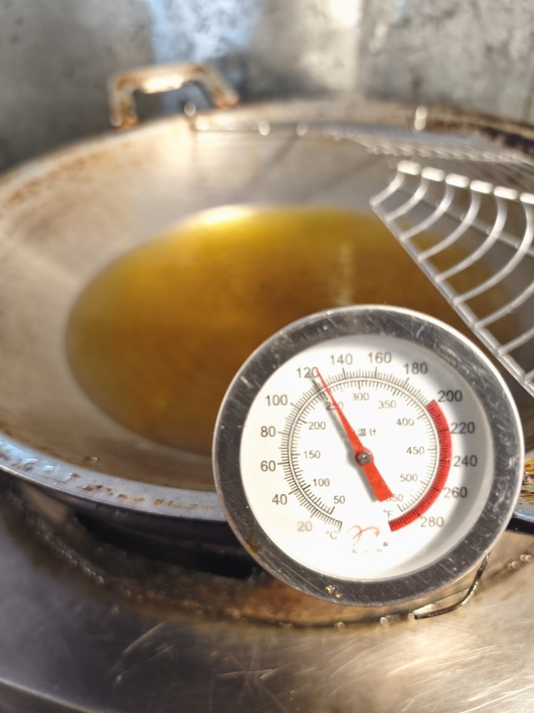 Thermometer checking hot oil temperature for deep frying