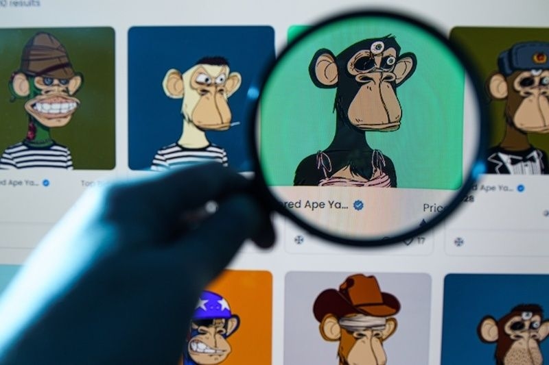 Magnifying glass highlighting a cartoon ape NFT among a grid of digital collectibles on a screen.