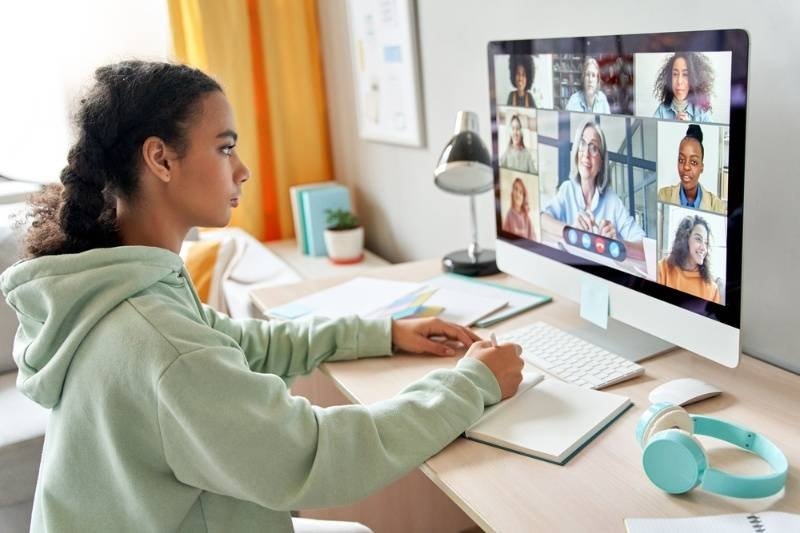 Student participating in a virtual class on a desktop computer with multiple classmates on a video call.