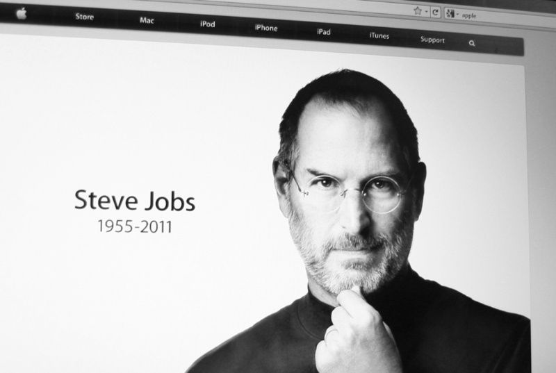 Black-and-white tribute image of Steve Jobs with birth and death years displayed on an Apple webpage.