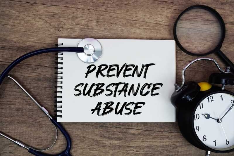 Notebook with ‘Prevent Substance Abuse’ text surrounded by a stethoscope and alarm clock.