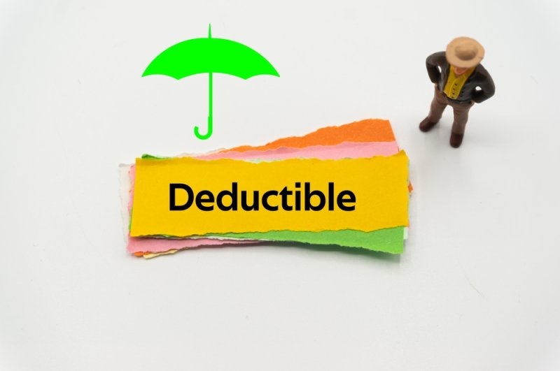 "Deductible" written on a yellow paper stripe with a green shadow of umbrella and a statue of a man.