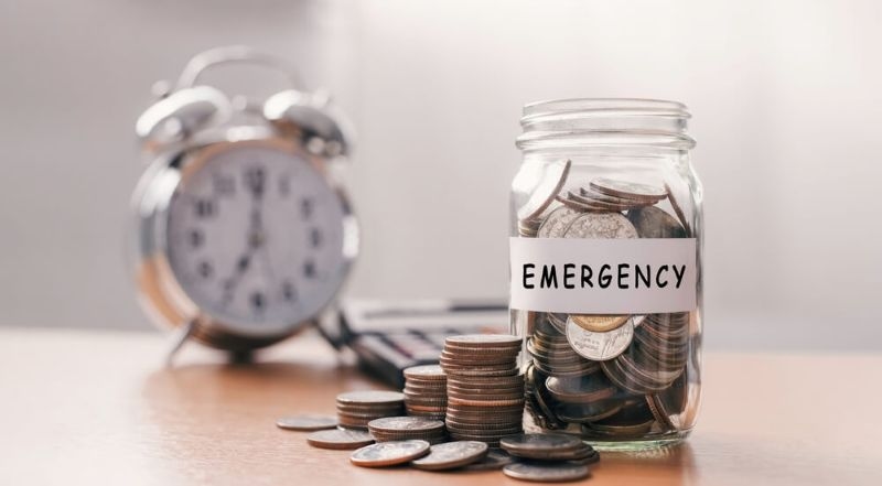 coins in a jar labelled with emergency on table