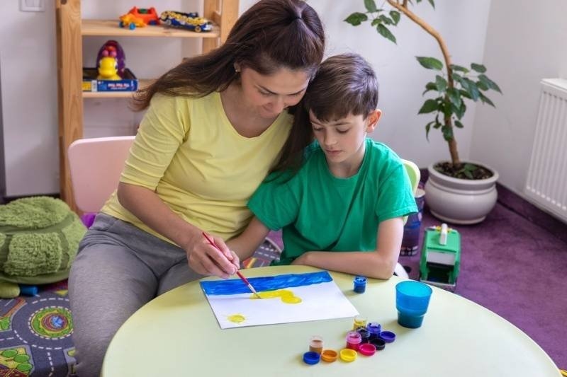 Mom helps her son draw at home.