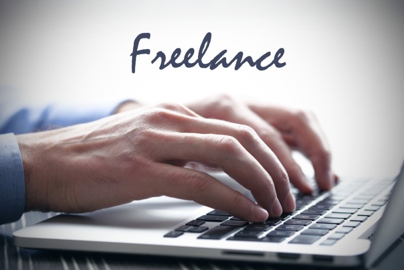 A close-up of hands typing on a laptop with the word “Freelance” displayed above.