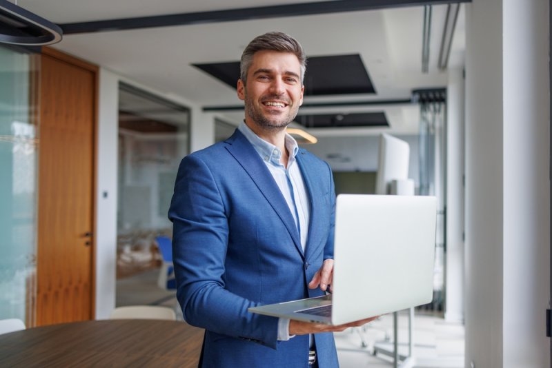Business professional holding a laptop in a modern office.