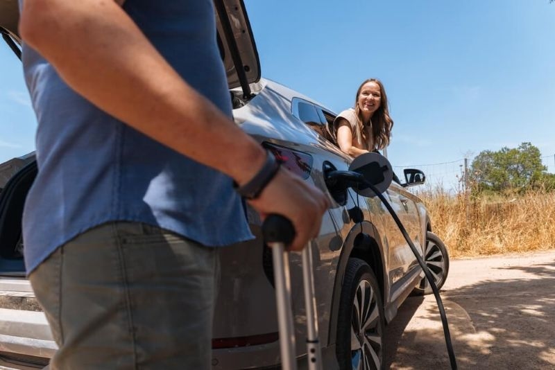 woman leaning outside the window from her ev which is charging