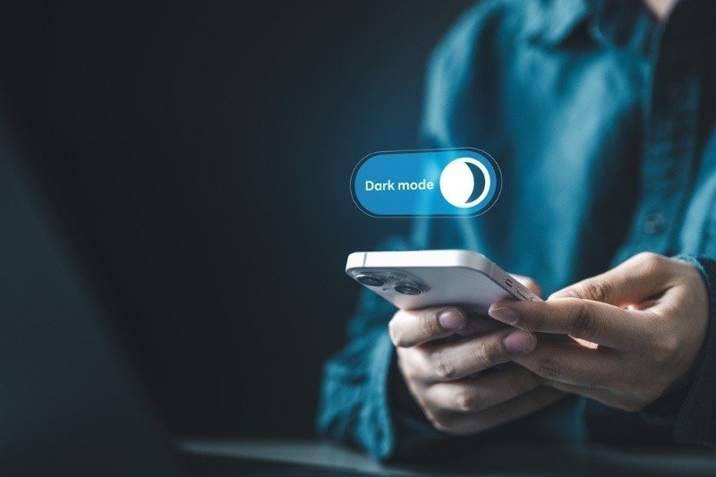 User enabling dark mode on smartphone interface for night viewing and visual comfort.