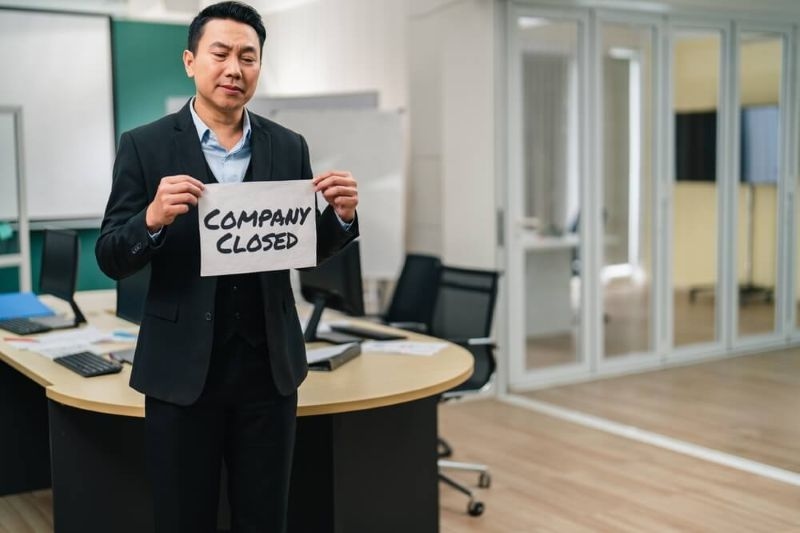 asian businessman holding company closed board in office