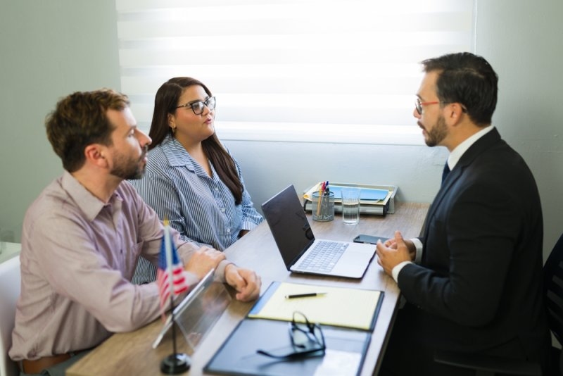 Young couple meeting with immigration lawyer, discussing legal process and receiving professional advice for their future.