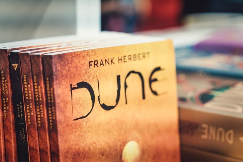A close-up of a “Dune” book by Frank Herbert alongside other books.