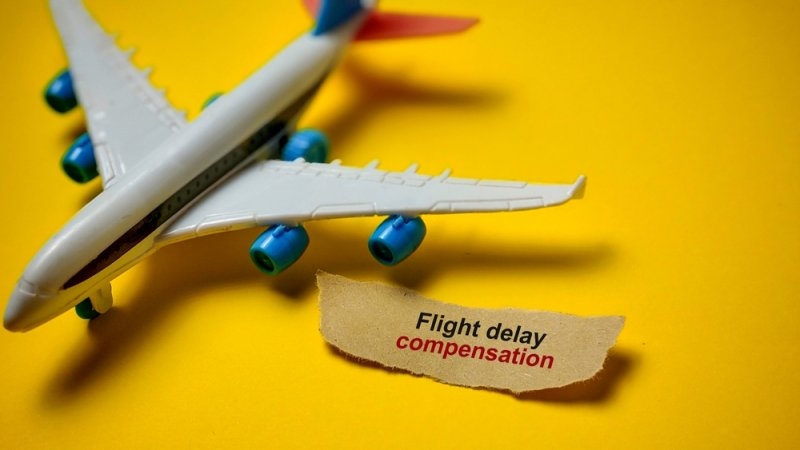 A model airplane beside a sign reading “Flight delay compensation.”