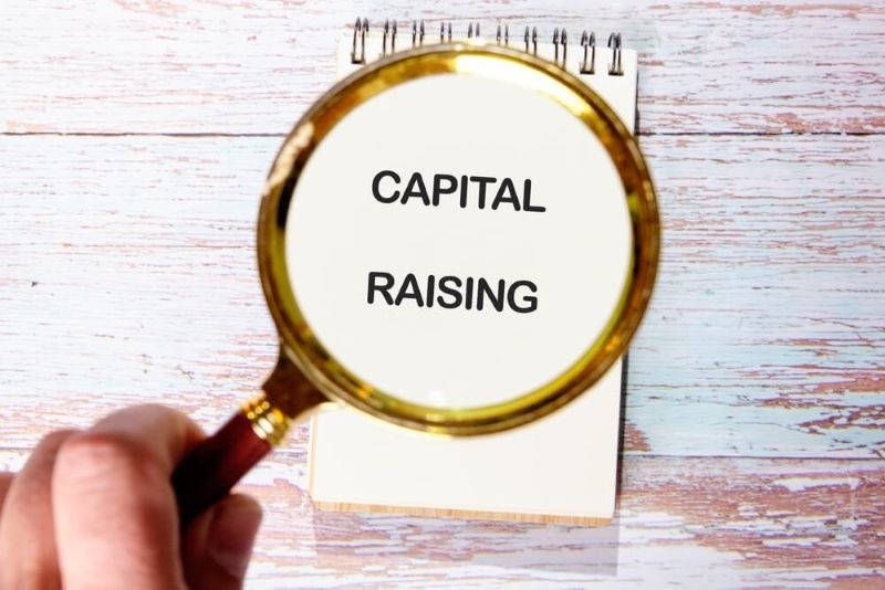 magnifying glass in hand focused on capital raising text