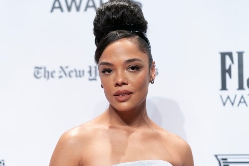 Tessa thompson with an elegant updo hairstyle posing on a red carpet at a fashion or awards event.