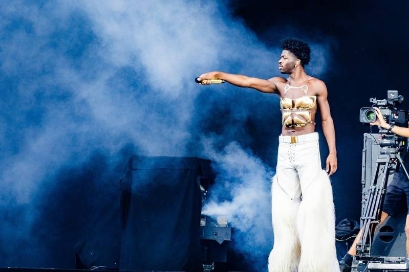 Singer performing on stage with a microphone and dramatic smoke effects during a concert.
