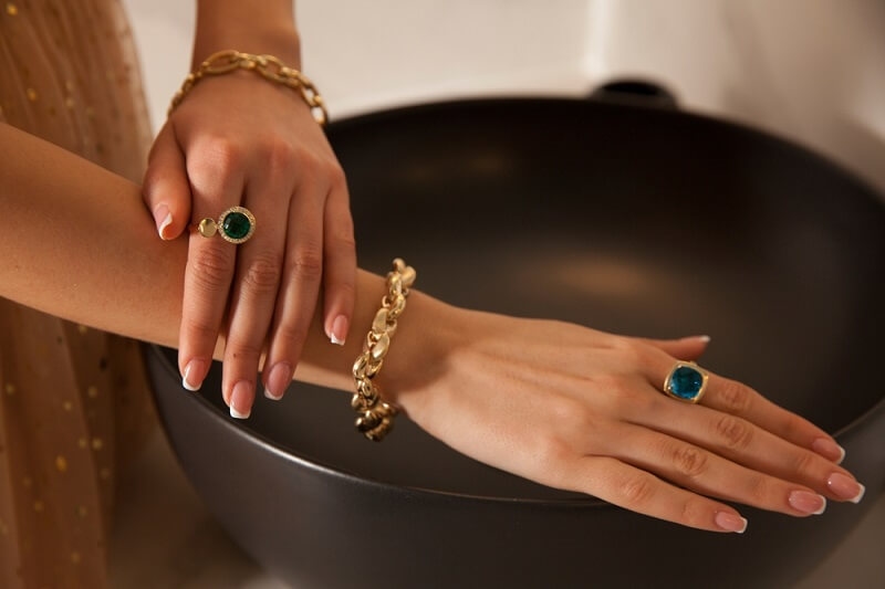 woman wearing gemstone ring in both hand fingures
