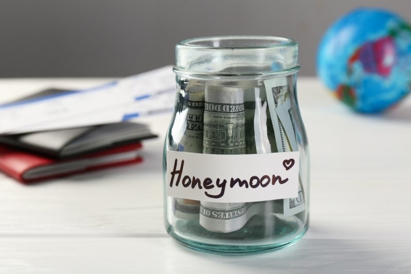 A glass jar filled with money labeled “Honeymoon.”