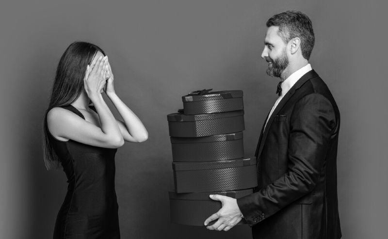 Man giving gifts to his girlfriend who has her eyes covered 