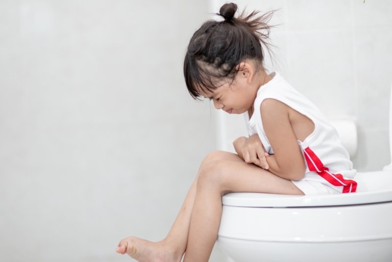 girl sitting on the toilet suffering from constipation