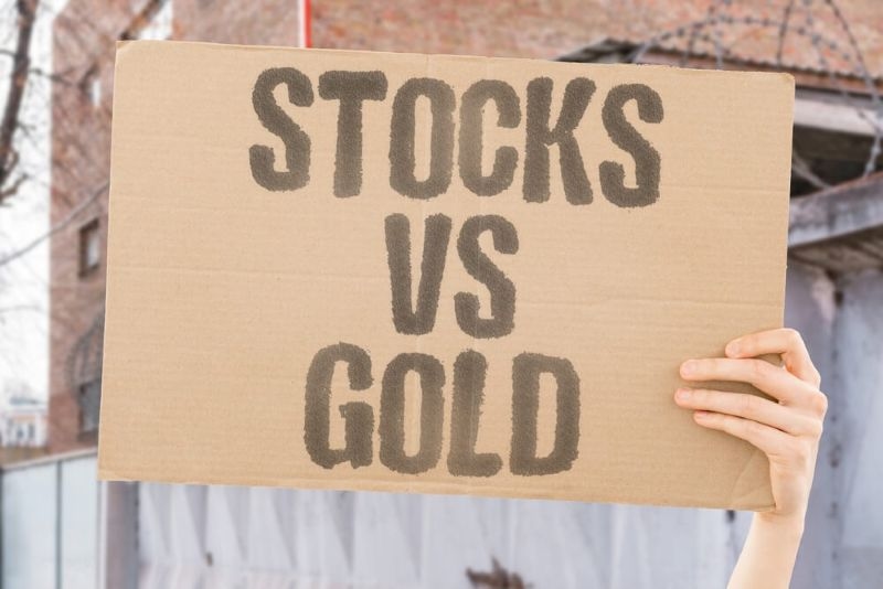 Text Stocks vs Gold written on a cardboard piece