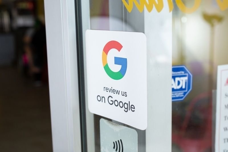 Storefront door displaying a “Review us on Google” sign, encouraging customers to leave online reviews.
