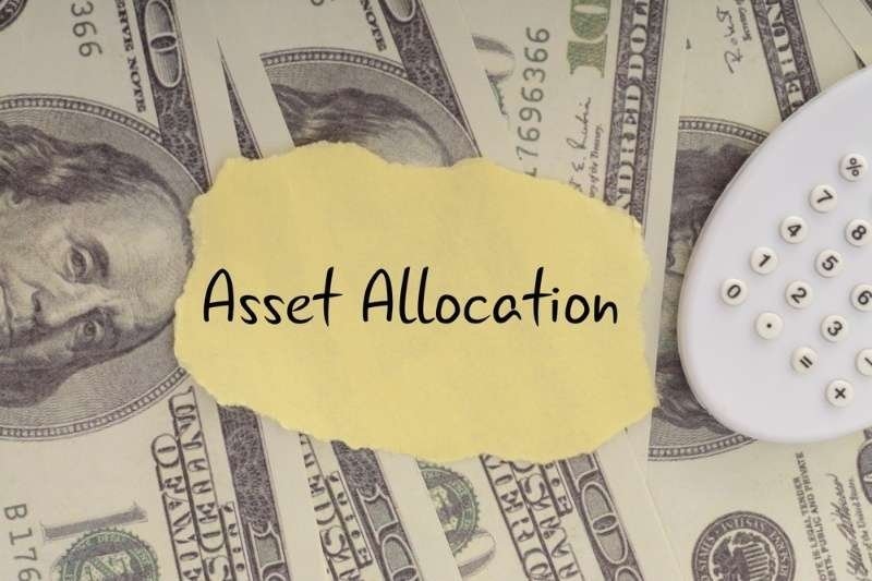 "Asset Allocation" note placed over U.S. dollar bills beside a calculator.