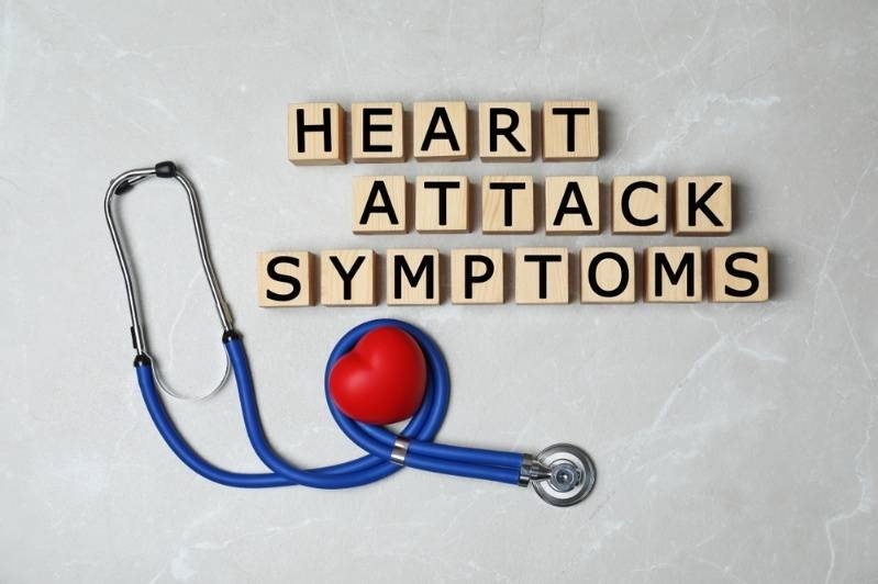 Stethoscope and red heart beside letter blocks spelling ‘Heart Attack Symptoms.