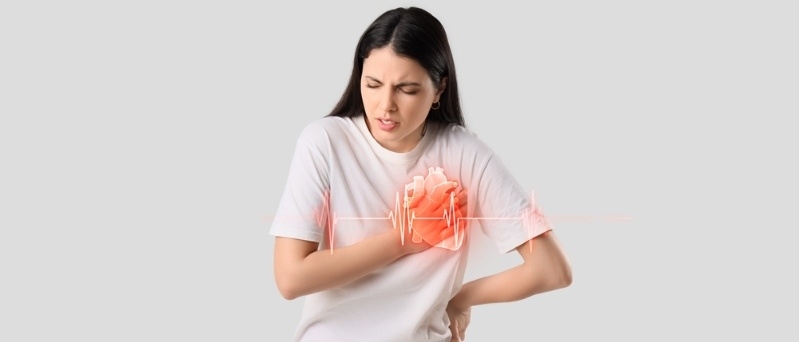 Woman clutching her chest in pain with highlighted heart area illustrating heart attack symptoms.