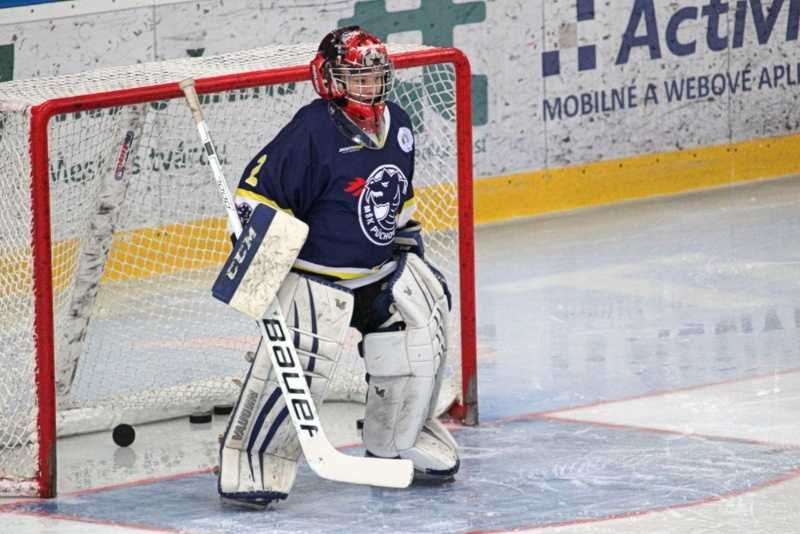 Ice hockey goalie standing in front of the net during a game on an indoor rink.