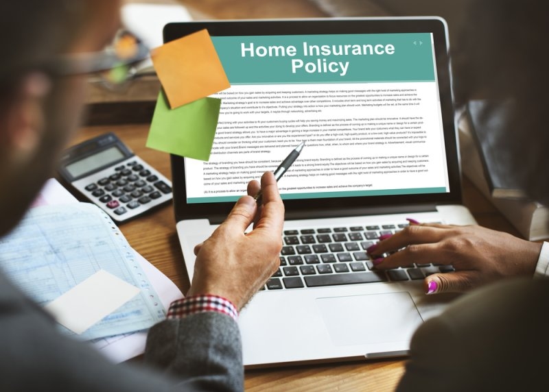 A laptop displaying a home insurance policy while people review the document together.