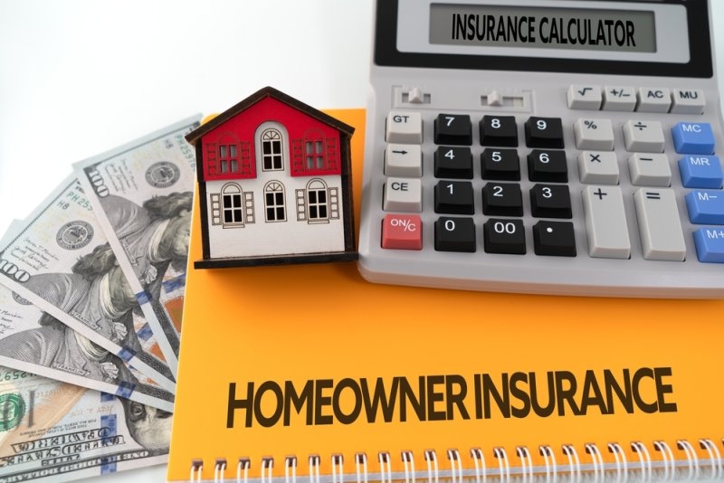 A small model house placed beside U.S. dollar bills and an “Insurance Calculator.”