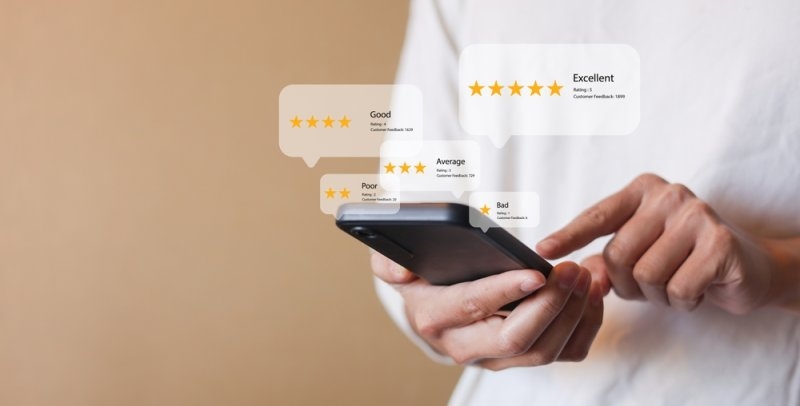 A person using a smartphone with floating five-star and customer rating icons.