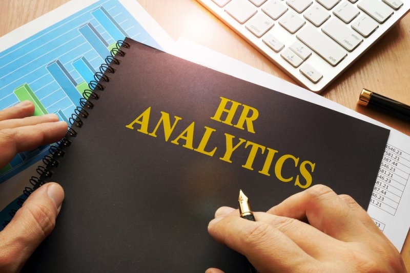 Notebook labeled “HR Analytics” with charts and a calculator on a desk.