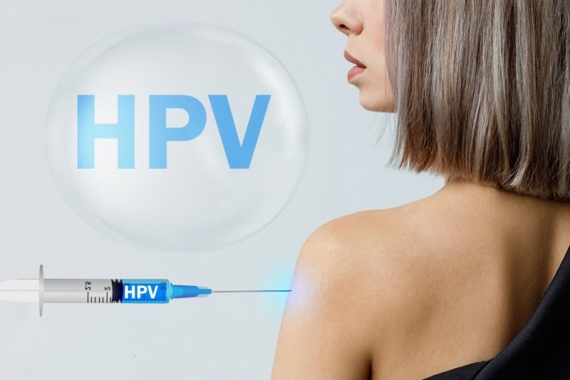 Woman receiving an HPV injection in the upper arm, with “HPV” displayed prominently in the background.
